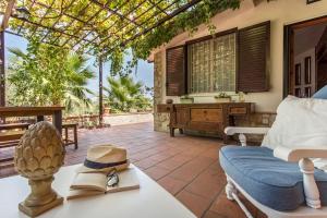 een patio met een tafel met een hoed en een stoel bij Sikelia Luxury Home in Altavilla Milicia