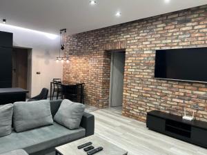 a living room with a couch and a brick wall at Raciborska Royal Apartment - miejsce parkingowe na parkingu strzeżonym in Gliwice