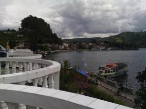 a river with a boat in the water at Darma Agung Beach Hotel Parapat in Parapat
