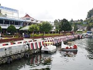 um grupo de barcos ancorados numa doca na água em Darma Agung Beach Hotel Parapat em Parapat