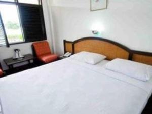 Darma Agung Beach Hotel Parapat في بارابات: غرفة نوم بسرير ابيض كبير وكرسي