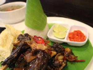 un plato de comida con carne y patatas fritas y salsa en Hotel Horison Kendari, en Puunggolaka
