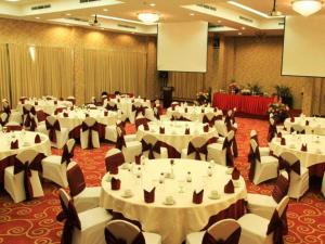 um grande salão de banquetes com mesas e cadeiras brancas em Hotel Horison Kendari em Puunggolaka