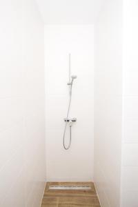 ein weißes Bad mit einer Dusche in der Wand in der Unterkunft Olive Tree Apartments 2 in Vodice