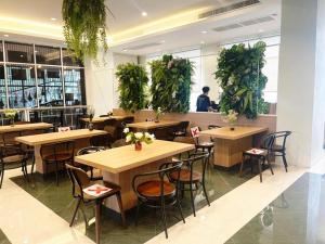 Valaya Hotel Pathumthani في Ban Lam Rua Taek: مطعم بالطاولات والكراسي والنباتات