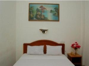 a bedroom with a bed with a picture on the wall at Hotel Bintang in Kampungdurian