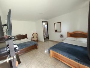 a hotel room with two beds and a tv at Hotel Campestre Cafetal - Quindio - EJE CAFETERO in Chorro Seco