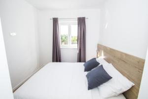 ein Schlafzimmer mit einem weißen Bett mit Kissen und einem Fenster in der Unterkunft Olive Tree Apartments 2 in Vodice + 61 Fotos