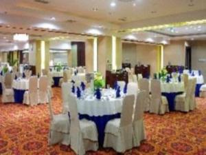 um salão de banquetes com mesas brancas e cadeiras brancas em Huzhou Zhebei Hotel em Huzhou