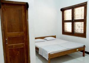 a bedroom with a bed and a door and a window at Hotel Wijaya Magelang in Magelang