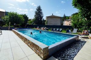 a swimming pool with people in the water at Logis Hotel Restaurant Family & Spa in Meyrueis