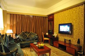 ein Wohnzimmer mit einem Sofa und einem TV in der Unterkunft Kunming Zhong Huang Hotel in Kunming