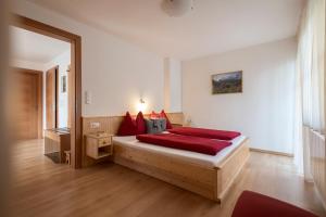 ein Schlafzimmer mit einem Bett mit roten Kissen in der Unterkunft Apartments Obereggerhof in Vals