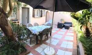 een patio met een tafel en stoelen en een parasol bij 89 Le Grand Pin in Sainte-Maxime