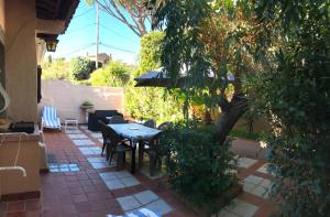 a patio with a table and chairs and a tree at 89 Le Grand Pin in Sainte-Maxime