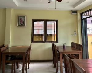 comedor con 2 mesas y sillas y 2 ventanas en Ponburi Hotel en Nan