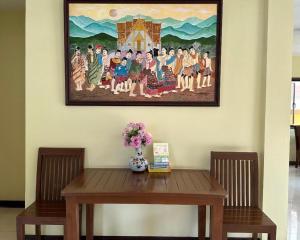 une peinture sur le mur au-dessus d'une table en bois dans l'établissement Ponburi Hotel, à Nan