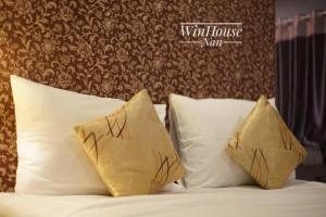 ナーンにあるWinhouse Hotelの白い枕と茶色の壁のベッド
