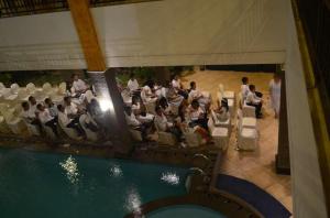 a group of people sitting in chairs next to a pool at Hotel Grande Lampung in Lampung