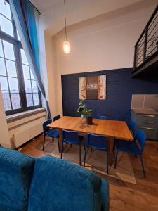 a living room with a wooden table and blue chairs at RedCity LOFT 430 in Żyrardów