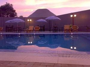 una piscina con mesas, sillas y sombrillas en Grand Wisata Hotel en Ende