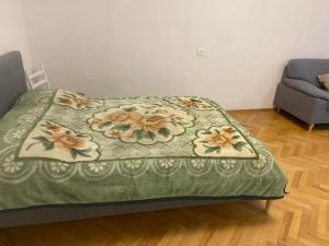 a bed with a green blanket with flowers on it at Шотико Квартира in Tbilisi City