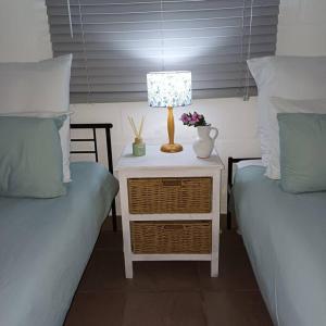 a lamp on a night stand next to two beds at Ria's Rest Self Catering Flatlet in Sedgefield