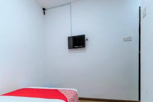a room with a white wall with a tv on it at OYO 90375 Reggae Inn in Bintulu