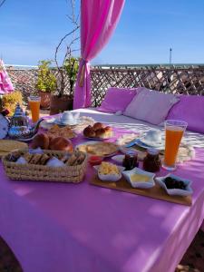 a table with a purple table cloth with food on it at Riad Sanaa Rose in Fez