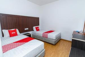 a hotel room with two beds with red and white sheets at OYO 90375 Reggae Inn in Bintulu