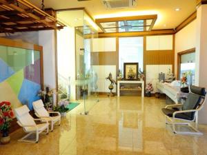 una gran sala de estar con sillas y una habitación con cama en Chodkamol Place 57, en Nakhon Si Thammarat
