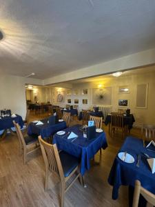 ein Esszimmer mit blauen Tischen und Stühlen in der Unterkunft Winchmore Hotel in Llandudno
