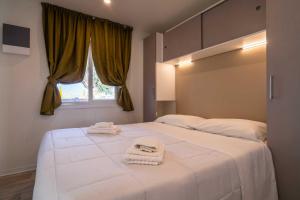 sypialnia z dużym białym łóżkiem z ręcznikami w obiekcie La Risacca Family Camping Village w mieście Porto SantʼElpidio