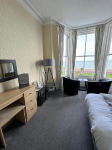 a hotel room with a bed and a desk and windows at Winchmore Hotel in Llandudno