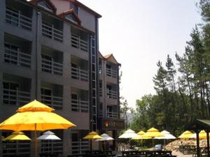 a group of tables with yellow umbrellas in front of a building at Mangsang Haeorum Family Hotel in Donghae