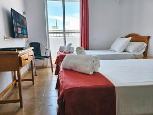 a room with two beds and a desk and a television at San Vicente Conil in Conil de la Frontera