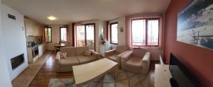 Una sala de estar con un sofá y sillas y un televisor. en Gri's place, en Bansko