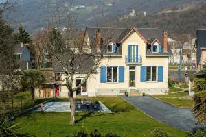 uma grande casa branca com persianas azuis em La maison des gaves - Calme, Agréable, Local vélo em Pierrefitte-Nestalas