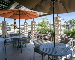 dwa stoły i krzesła z parasolami na patio w obiekcie Sleep Inn & Suites w mieście Dripping Springs