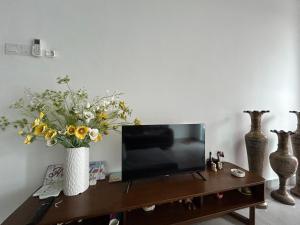 una sala de estar con TV y un jarrón de flores en P3 Great value, cozy, convenient in city!, en Kuching