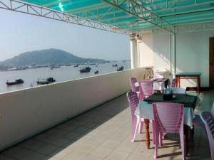 a balcony with tables and chairs and a view of a river at Mya See Sein Hotel in Myeik