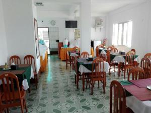 a dining room with tables and chairs and a kitchen at Mya See Sein Hotel in Myeik