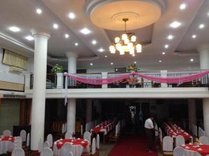sala bankietowa z czerwono-białymi stołami i krzesłami w obiekcie Mya See Sein Hotel w mieście Myeik