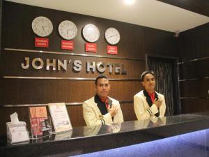 John's Hotel في Maulafa: رجلين واقفين امام كونتر بالساعات