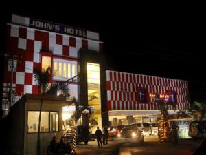 John's Hotel في Maulafa: فندق فيه مبنى احمر وابيض بالليل