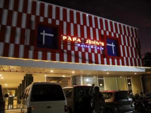 John's Hotel في Maulafa: محل بيتزا فيه سيارات متوقفة أمامه