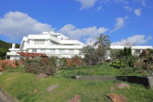 a white building on top of a grassy hill at Ashizuri Onsen Ashizuri Sunnyside Hotel in Isa