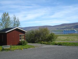 a small red building with a bench next to a field at Guesthouse P&eacute;tursborg in Akureyri