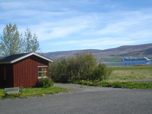 un pequeño edificio rojo con un banco junto a un campo en Guesthouse Pétursborg, en Akureyri