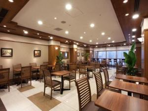豊岡市にあるToyooka Green Hotel Morrisの木製のテーブルと椅子が備わる空きレストランです。